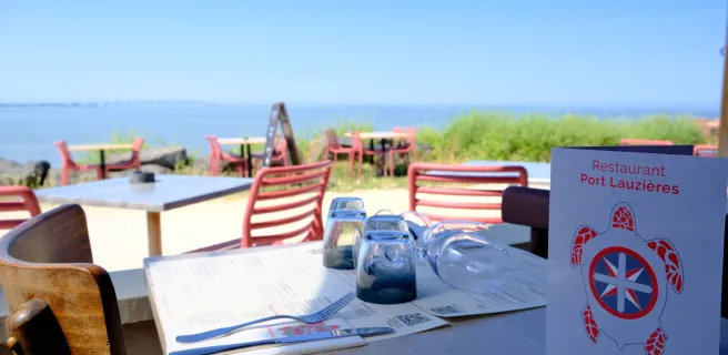 Zoom sur une table avec verres et menus, en face de l'océan.