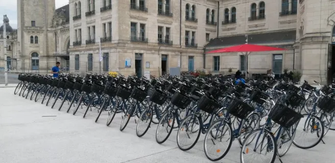 Devanture de la boutique, une cinquantaine de vélos bien rangés sur le parvis de la gare