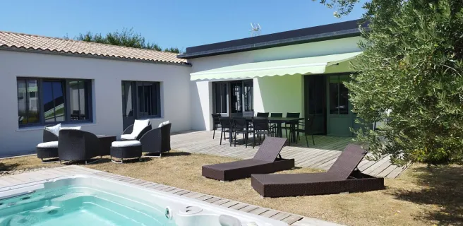 La piscine extérieure découverte, entourée par la maison, des salons de jardins et transats.