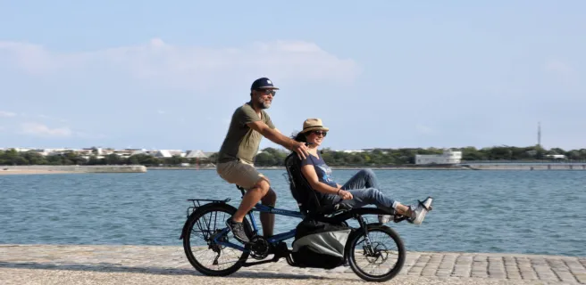 2 personnes sur un tandem en bord de mer